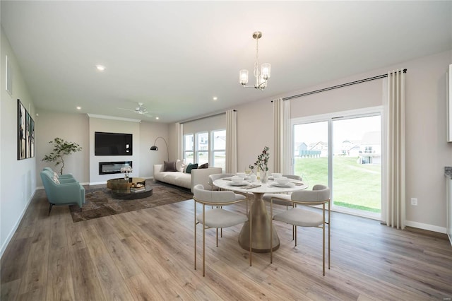 dining area with ceiling fan with notable chandelier and light hardwood / wood-style flooring