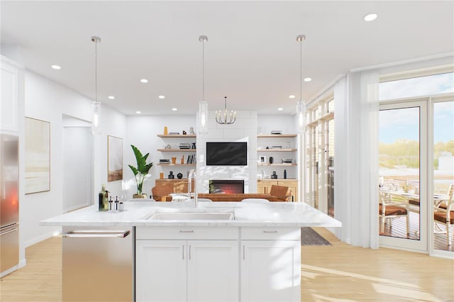 kitchen featuring decorative light fixtures, a fireplace, light hardwood / wood-style flooring, white cabinetry, and sink