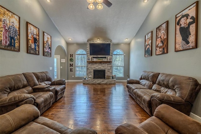 living room with ceiling fan, dark hardwood / wood-style floors, lofted ceiling, a textured ceiling, and a fireplace