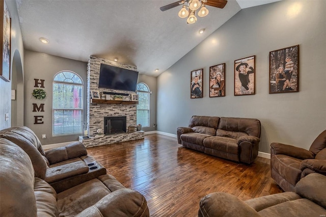 living room with dark hardwood / wood-style floors, ceiling fan, a textured ceiling, and a stone fireplace