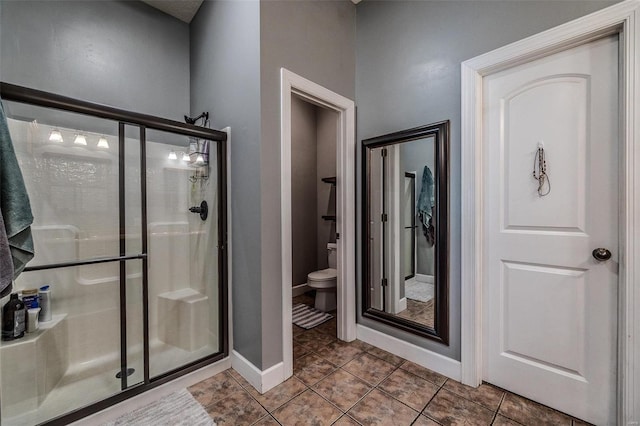 bathroom featuring tile floors, toilet, and a shower with shower door