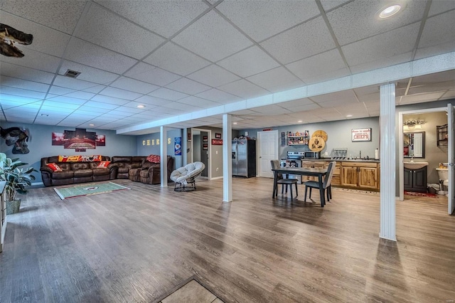 rec room with a drop ceiling, ornate columns, and hardwood / wood-style flooring