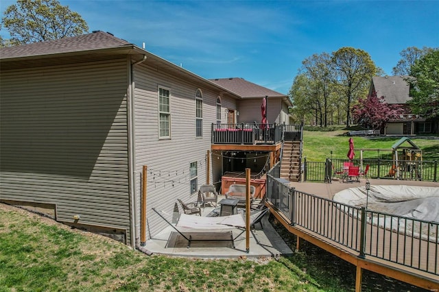 rear view of house with a patio, a wooden deck, and a lawn