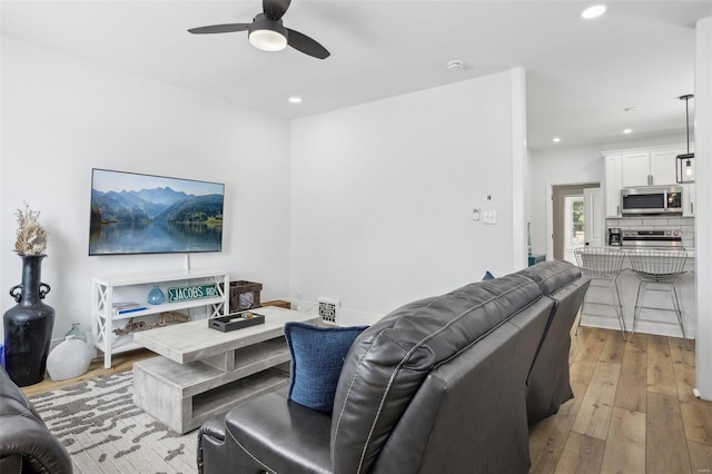 living room with light hardwood / wood-style flooring and ceiling fan