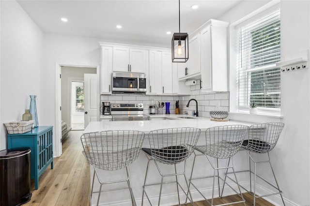 kitchen with plenty of natural light, white cabinetry, kitchen peninsula, hanging light fixtures, and stainless steel appliances