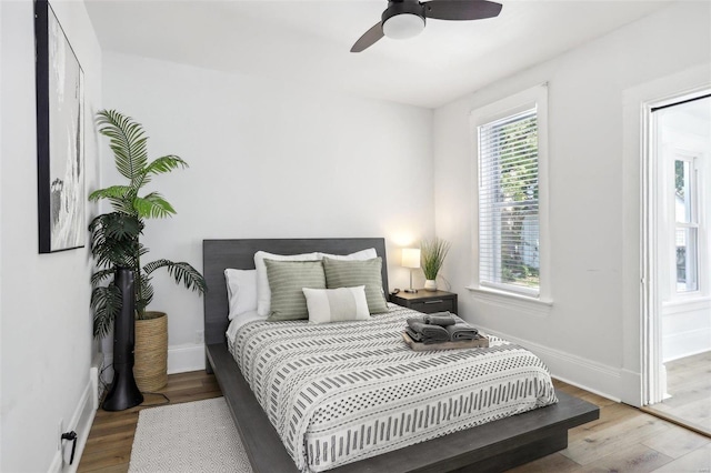 bedroom with ceiling fan, light wood-type flooring, and multiple windows