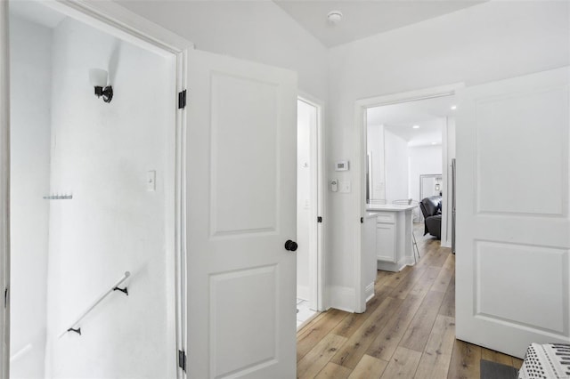 hallway featuring light wood-type flooring and lofted ceiling