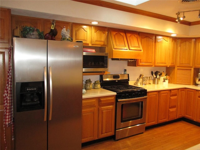 kitchen featuring appliances with stainless steel finishes, light hardwood / wood-style flooring, and crown molding