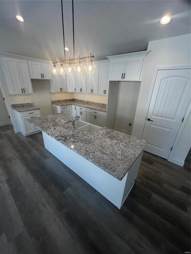 kitchen with hanging light fixtures, an island with sink, dark hardwood / wood-style flooring, white cabinets, and sink