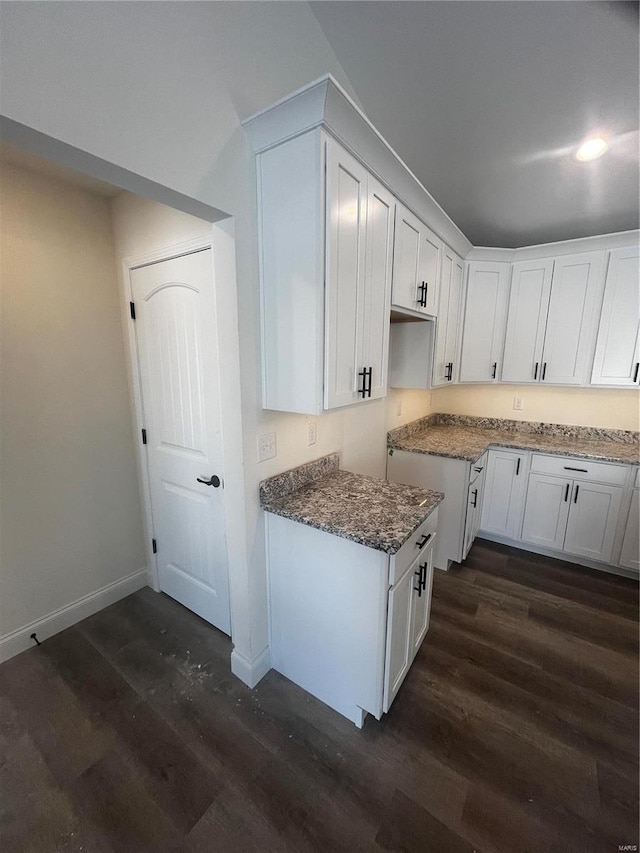 kitchen with dark stone counters, dark wood-type flooring, and white cabinetry