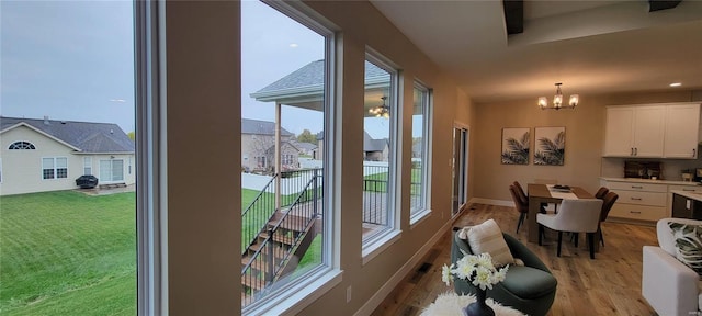 entryway with a notable chandelier, a healthy amount of sunlight, and light hardwood / wood-style flooring