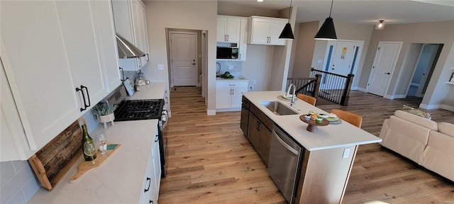 kitchen with sink, hanging light fixtures, a center island with sink, white cabinets, and light wood-type flooring