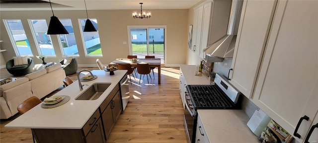 kitchen with decorative light fixtures, a center island with sink, and white cabinetry