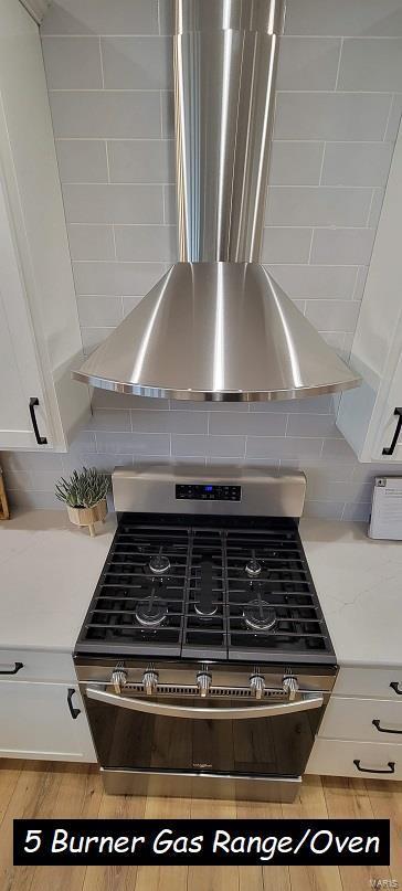 room details featuring gas range, light stone counters, and white cabinets