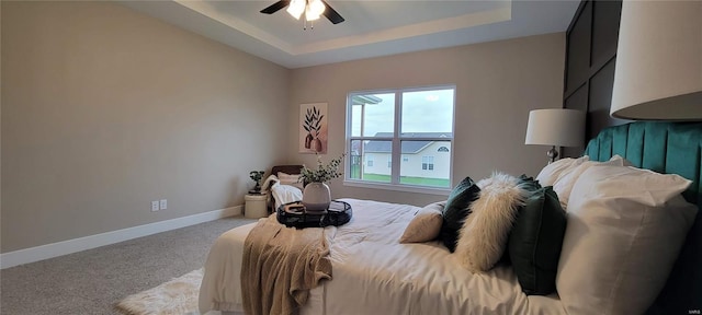 carpeted bedroom featuring ceiling fan and a raised ceiling