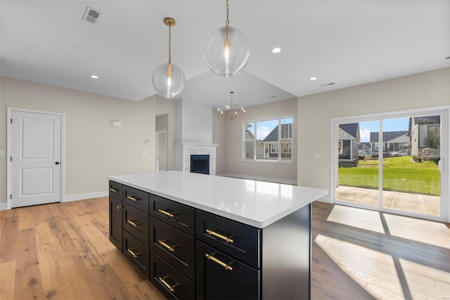 kitchen featuring a center island, decorative light fixtures, light hardwood / wood-style floors, and a fireplace