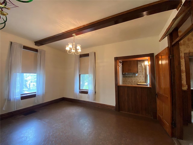 empty room with plenty of natural light, an inviting chandelier, and beamed ceiling