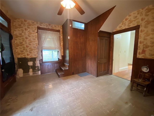 interior space featuring lofted ceiling, ceiling fan, and wooden walls