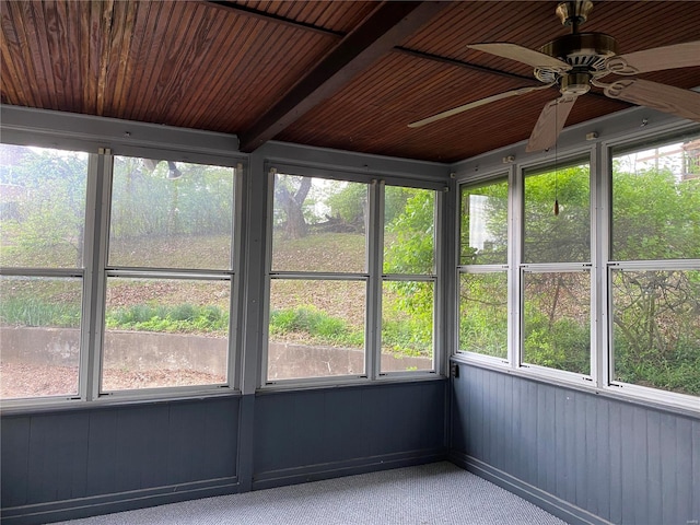 unfurnished sunroom featuring wood ceiling, a wealth of natural light, ceiling fan, and beam ceiling