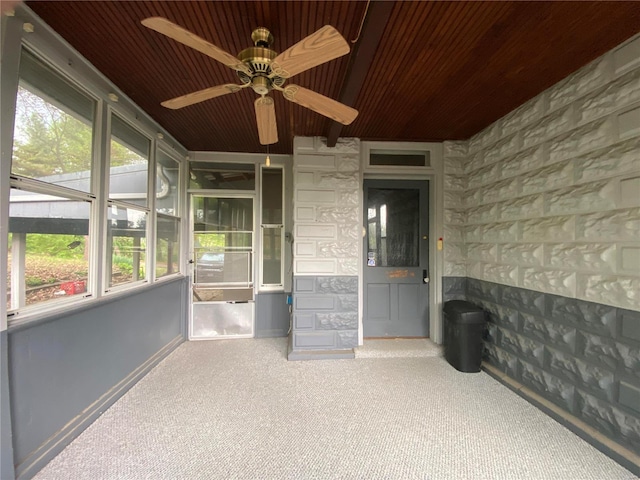 unfurnished sunroom featuring wood ceiling and ceiling fan