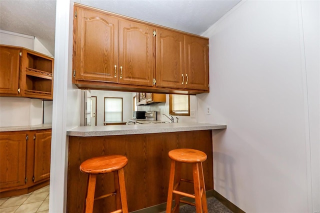 kitchen featuring sink, light tile floors, and a breakfast bar area