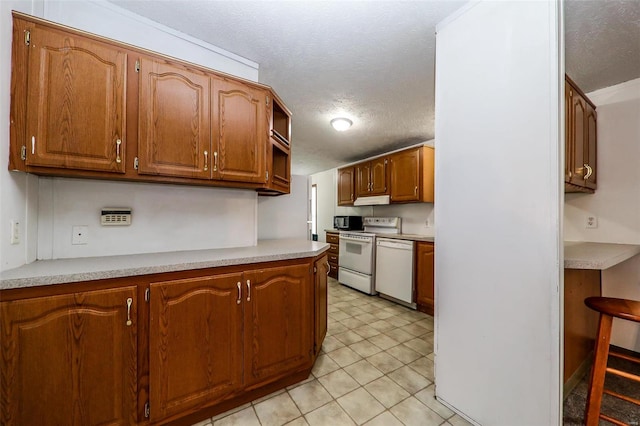 kitchen with a textured ceiling, white appliances, and light tile floors