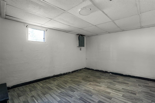 basement featuring electric panel, a drop ceiling, and dark wood-type flooring