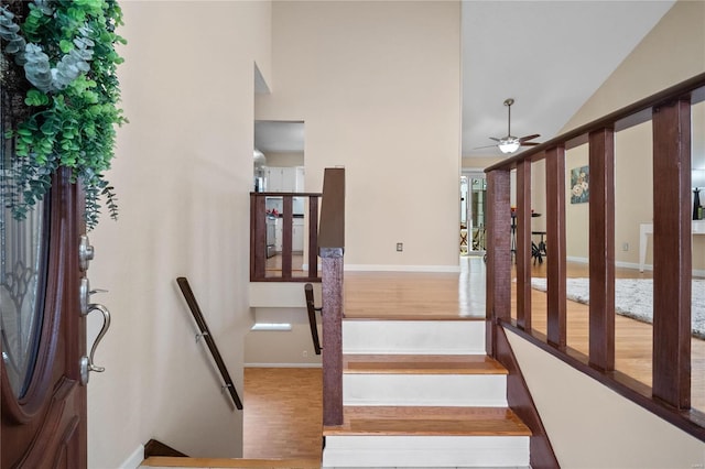 staircase with ceiling fan, wood-type flooring, and vaulted ceiling