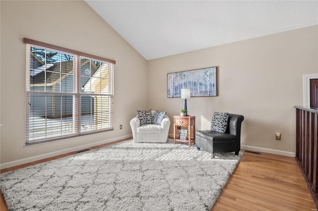 living area featuring lofted ceiling and light hardwood / wood-style floors