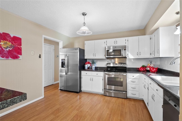 kitchen with sink, light hardwood / wood-style flooring, appliances with stainless steel finishes, a textured ceiling, and white cabinets