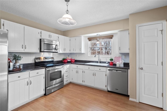 kitchen with a textured ceiling, sink, stainless steel appliances, and white cabinetry