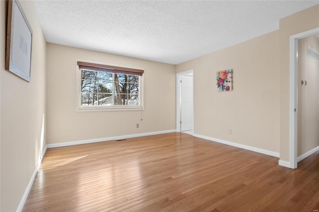 spare room featuring a textured ceiling and light hardwood / wood-style floors