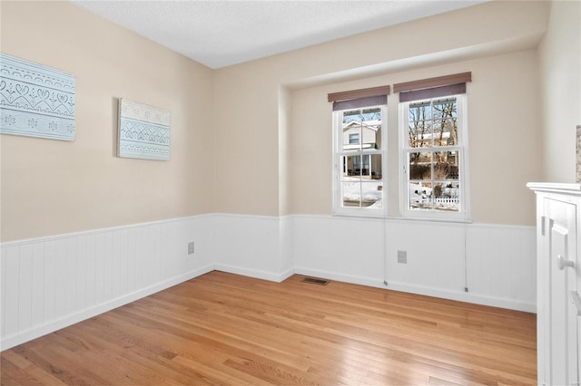 unfurnished room featuring a textured ceiling and light hardwood / wood-style floors