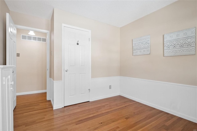 empty room featuring a textured ceiling and light hardwood / wood-style flooring