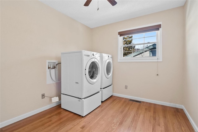 washroom with washing machine and dryer, ceiling fan, a textured ceiling, and light wood-type flooring