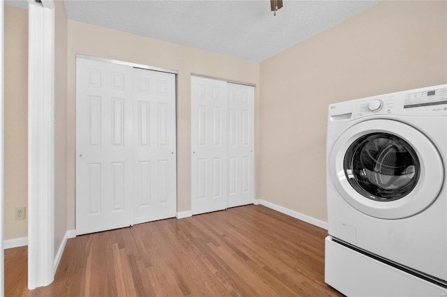 clothes washing area featuring light hardwood / wood-style floors, a textured ceiling, and washer / dryer