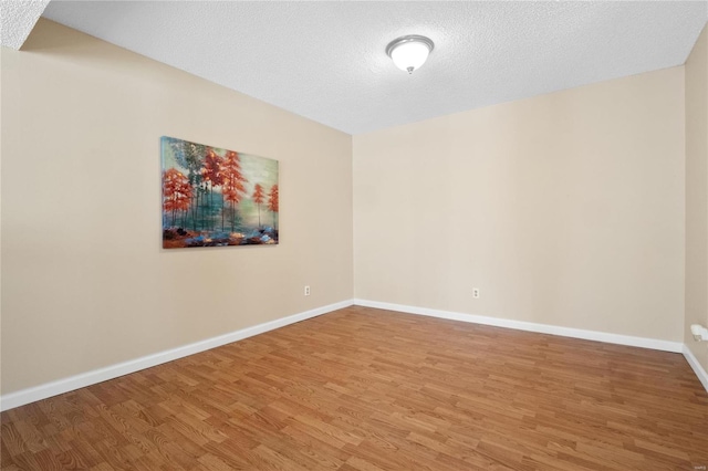 empty room with wood-type flooring and a textured ceiling