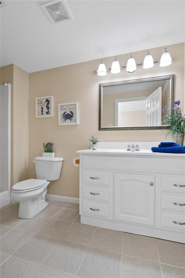 bathroom with toilet, vanity, and tile patterned floors