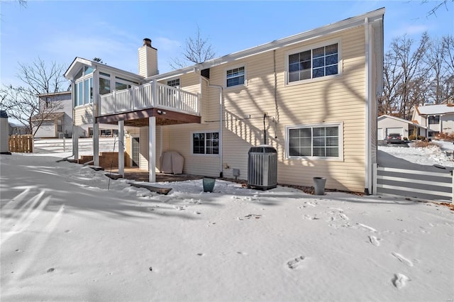 snow covered house featuring central air condition unit and a wooden deck