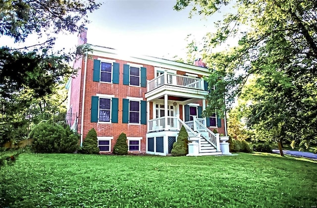 rear view of property with a balcony and a lawn