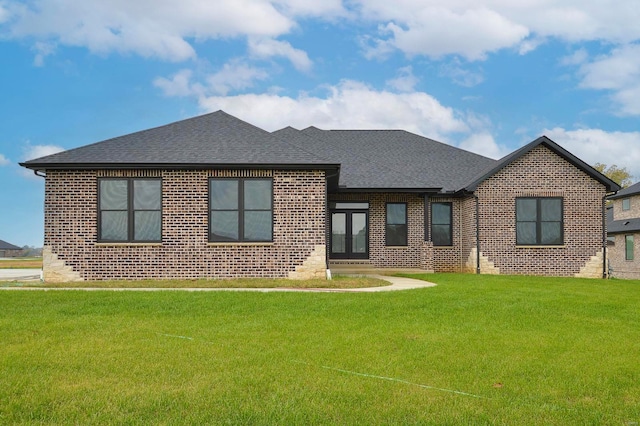 view of front of home featuring brick siding, a shingled roof, and a front lawn