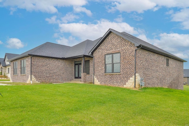 ranch-style house with brick siding, a front yard, and a shingled roof