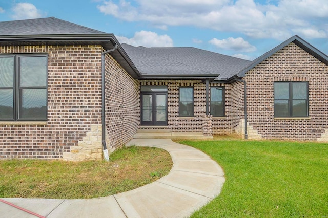 view of front facade featuring brick siding, a front lawn, and roof with shingles