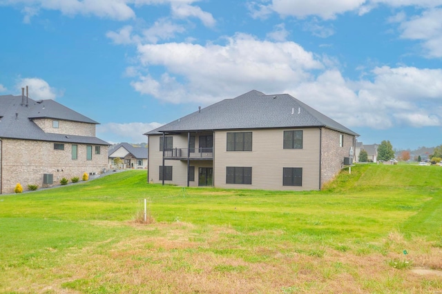 rear view of house with a lawn and a balcony