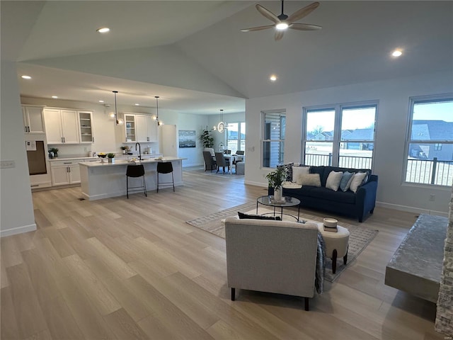 living area with baseboards, recessed lighting, light wood-style flooring, high vaulted ceiling, and a ceiling fan