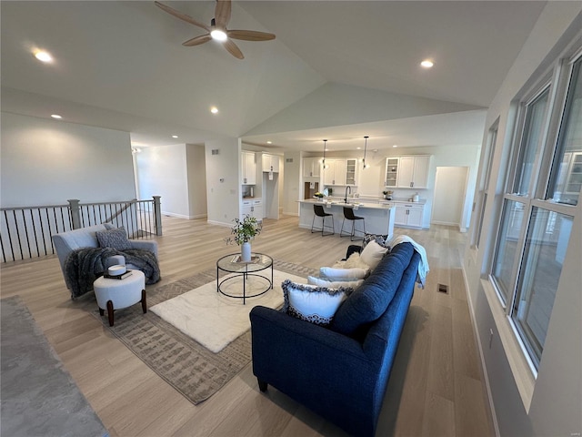 living area featuring baseboards, light wood-type flooring, recessed lighting, high vaulted ceiling, and a ceiling fan