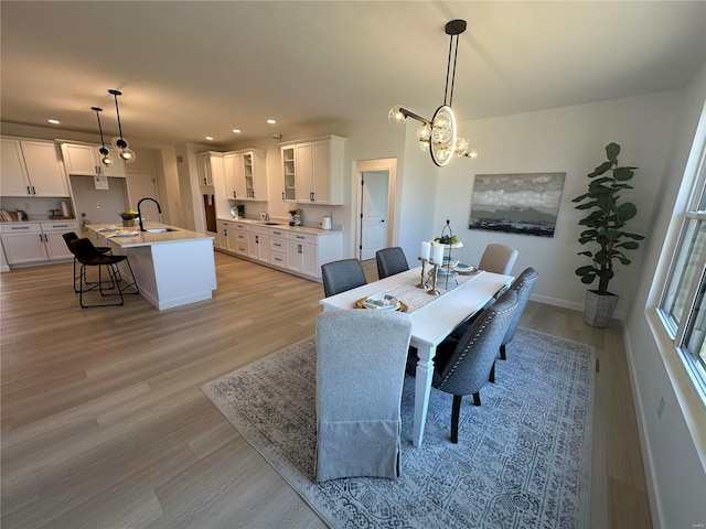 dining room with recessed lighting, baseboards, light wood-style floors, and an inviting chandelier