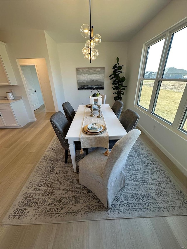 dining space featuring a notable chandelier, baseboards, and light wood finished floors