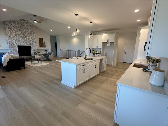 kitchen featuring open floor plan, white cabinets, light wood-type flooring, and a sink