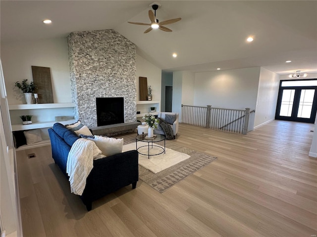 living room featuring light wood finished floors, high vaulted ceiling, recessed lighting, ceiling fan, and a stone fireplace